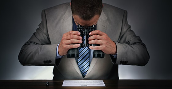 man reading document with binoculars