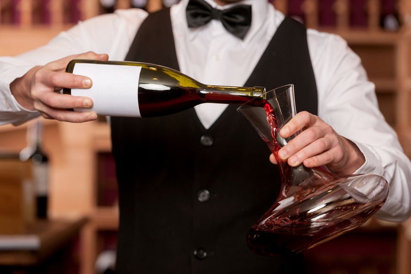 waiter pouring red wine into decanter