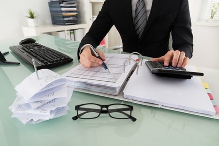 man looking through binder with calculator