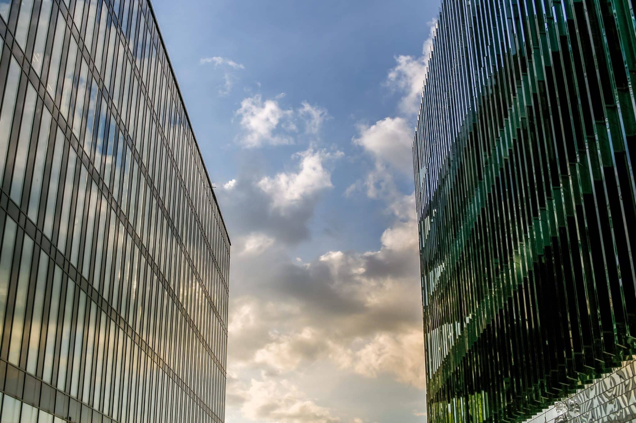 two large modern buildings stand close to each other, closing the sky