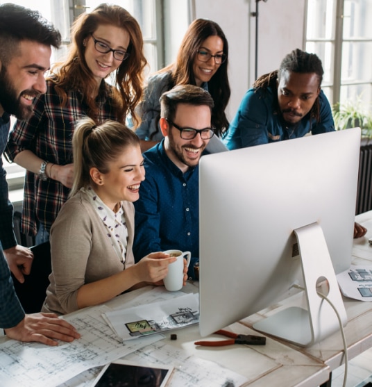 Happy group of coworkers looking at a desktop computer