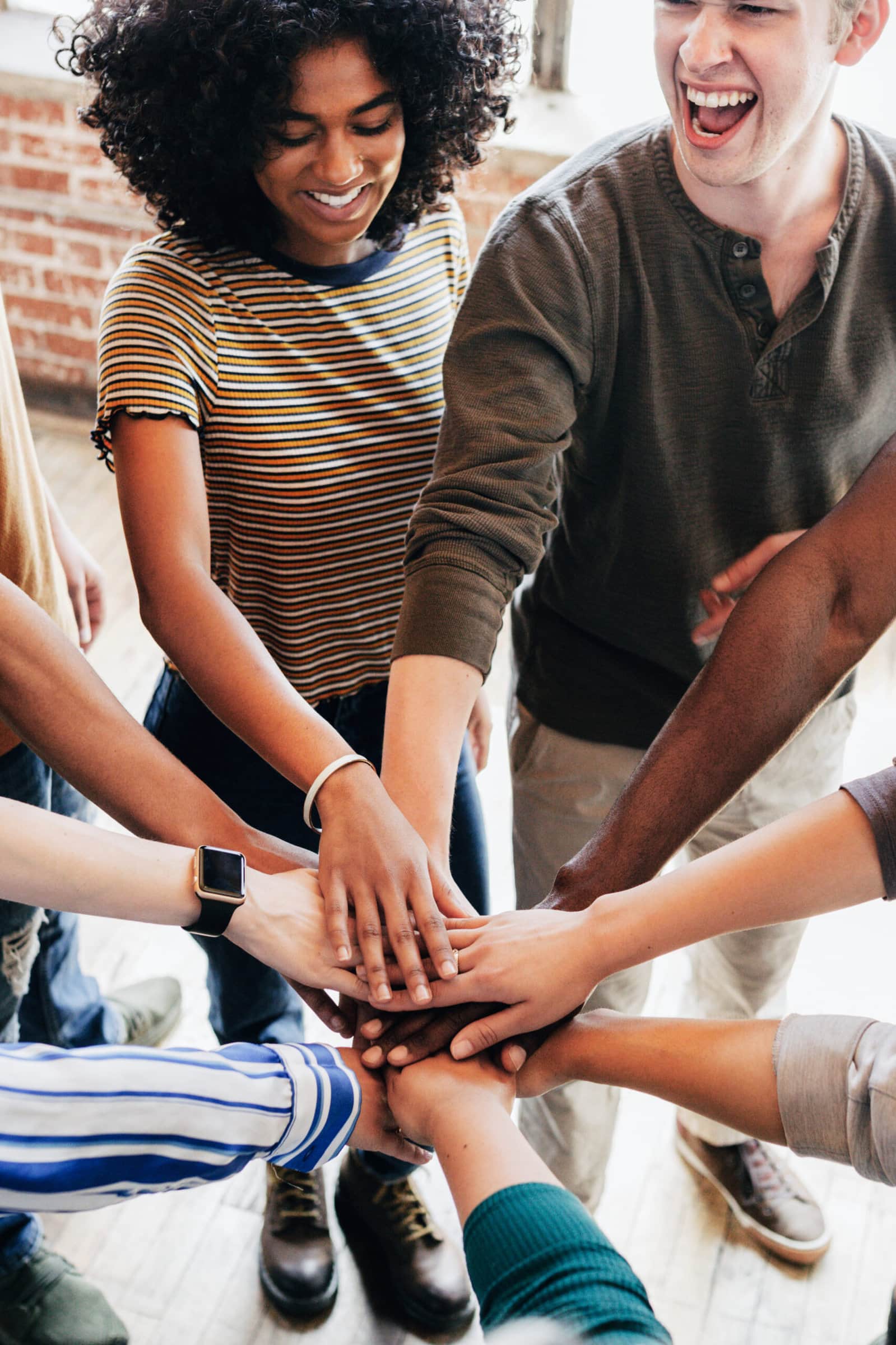 Group of happy diverse people stacking hands