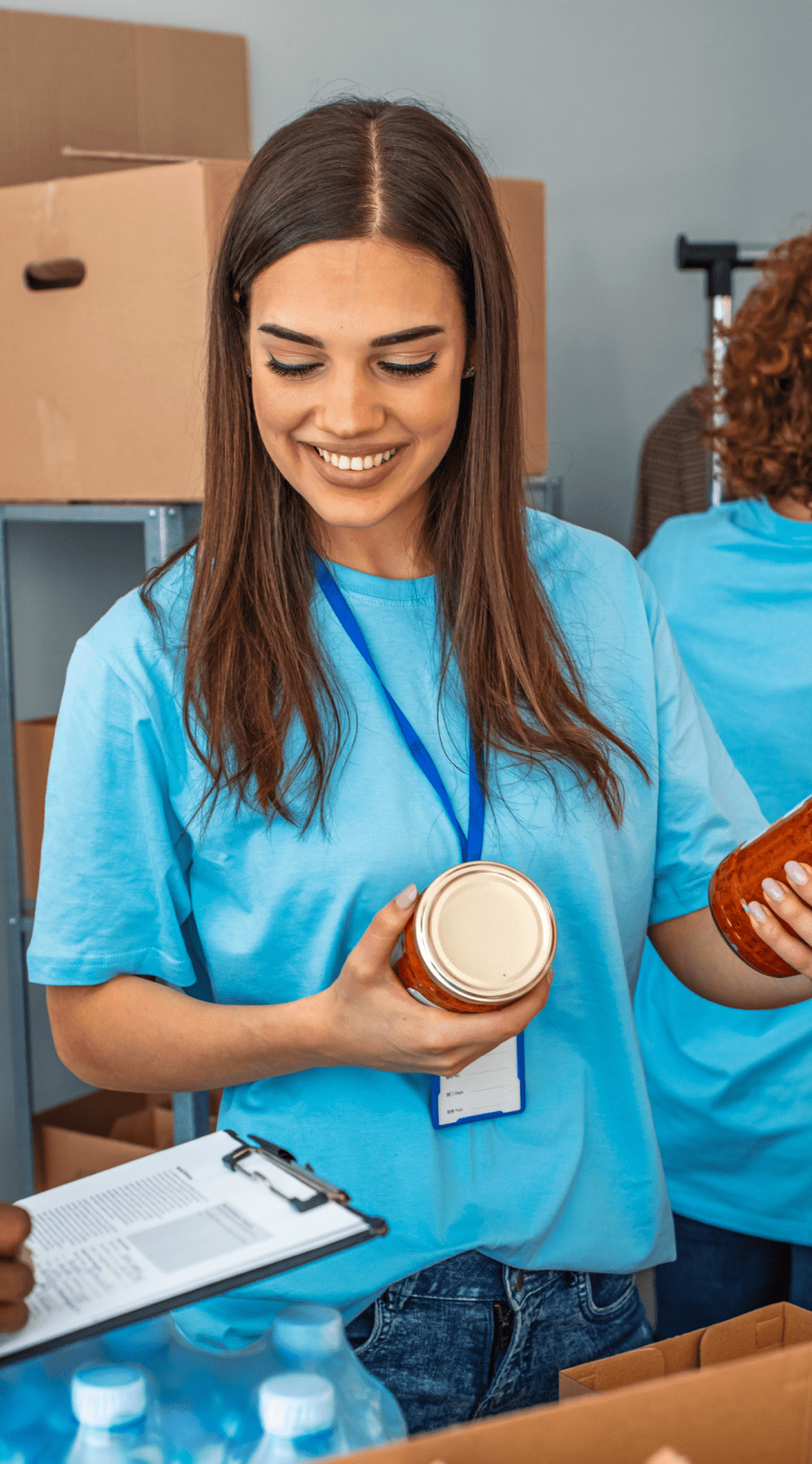 woman volunteering at a foodbank with cans of food in her hand