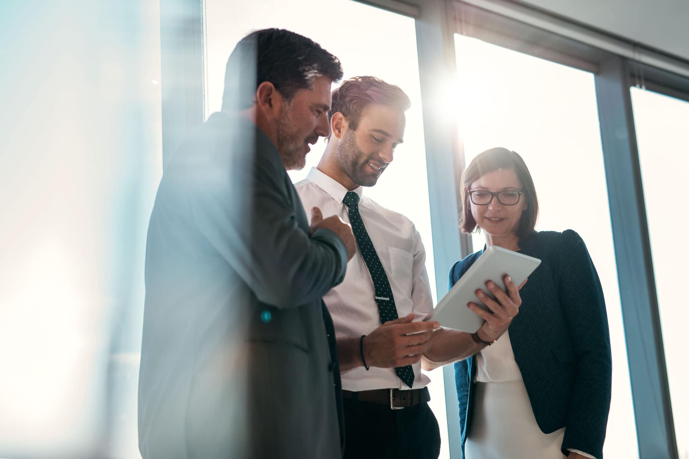 Three coworkers looking at a tablet together