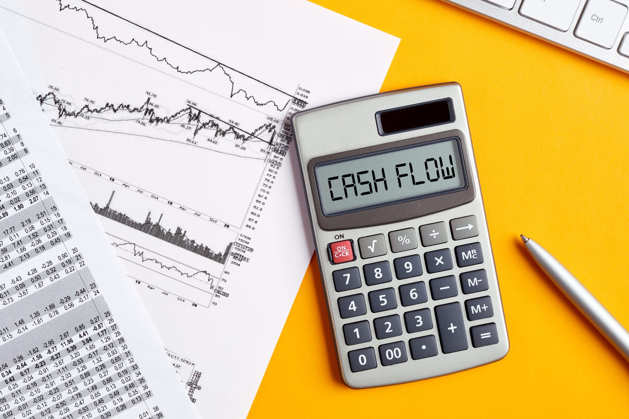 The word cash flow on calculator display screen with business office desktop. To calculate or analyze financial cash flow concept.