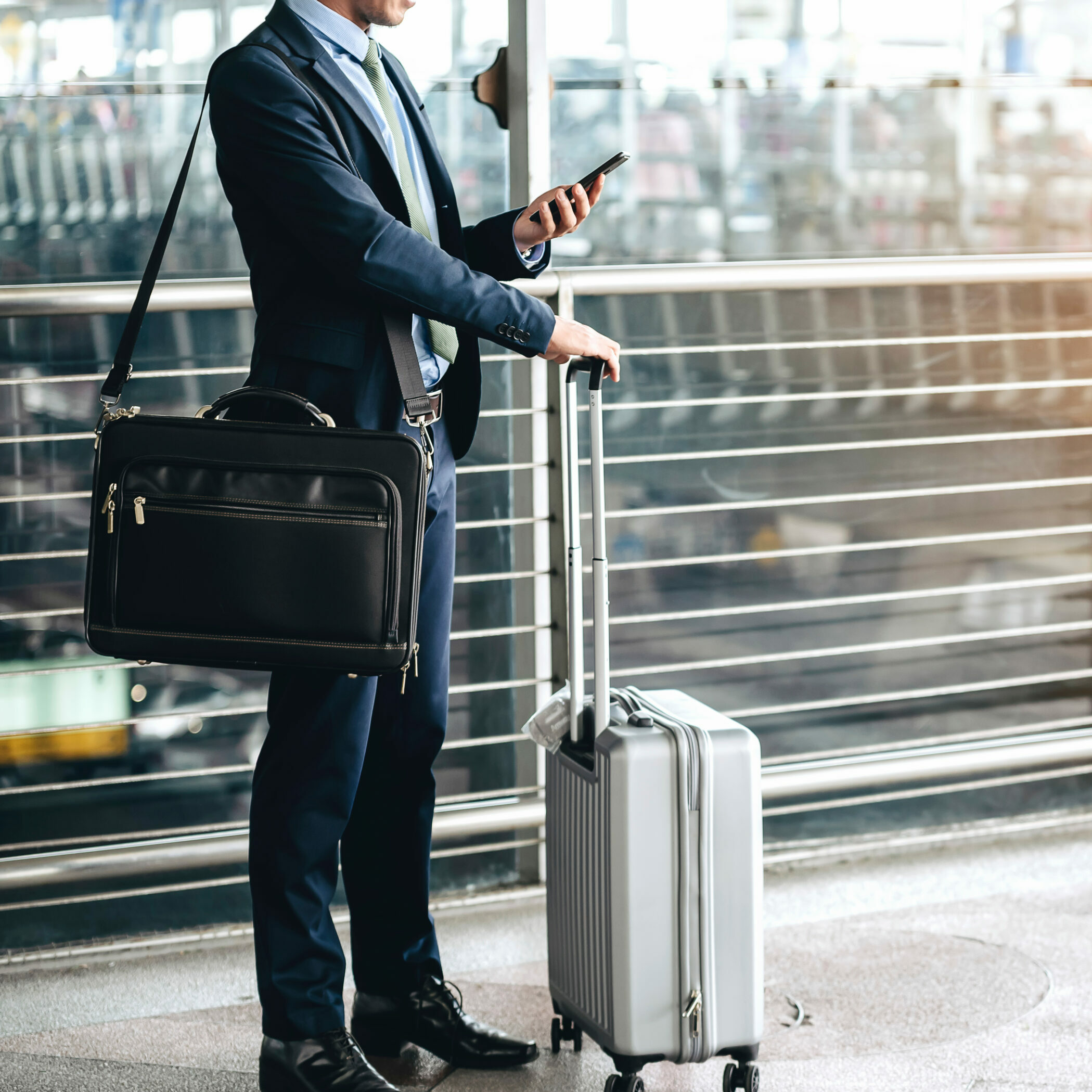 An Asian businessman is using a smartphone to get in business while waiting for a trip in the airport.