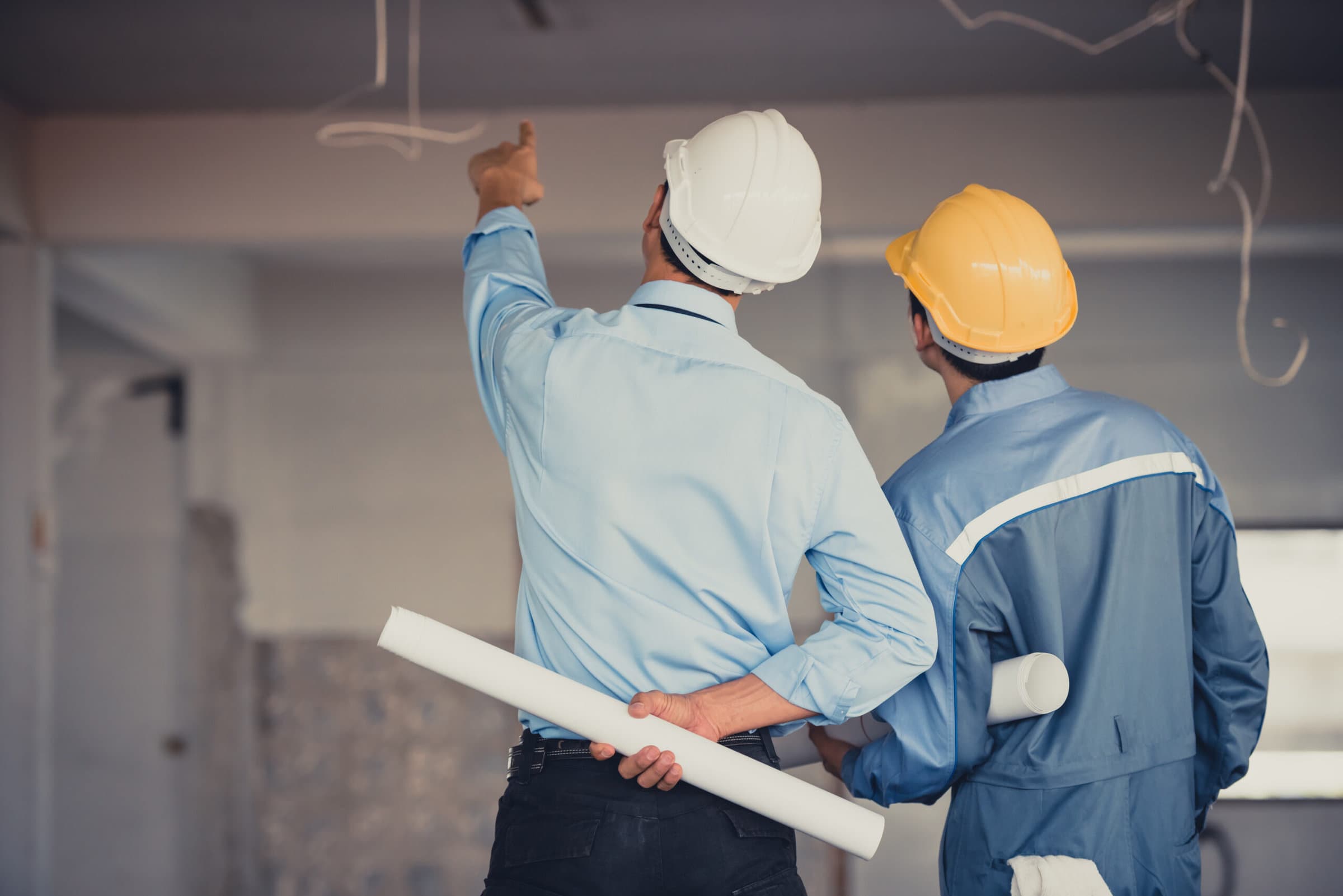 Engineer team with hard hat and blueprint talking together at th