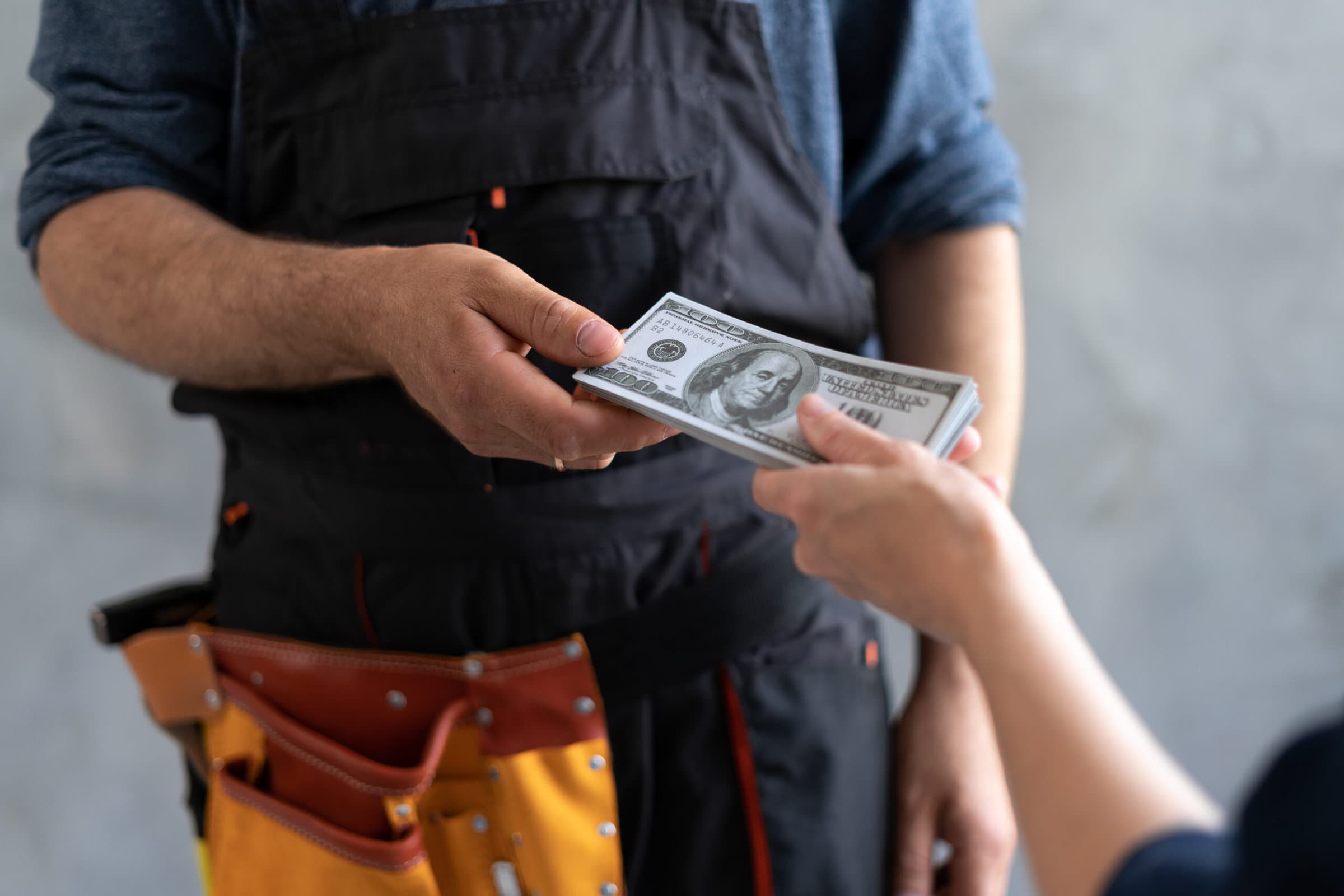 close-up female hand pays for the work of foreman builder repairman with dollar money. construction site concept. Focus on hands with money. business woman master deal.