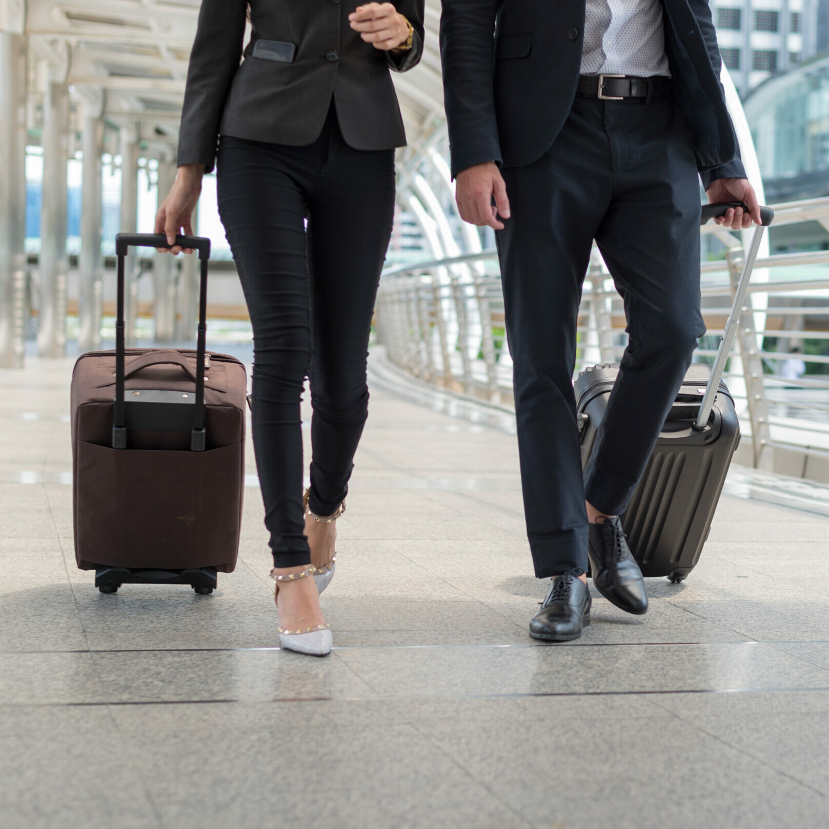 business man and business woman walk together luggage on the public street, business travel