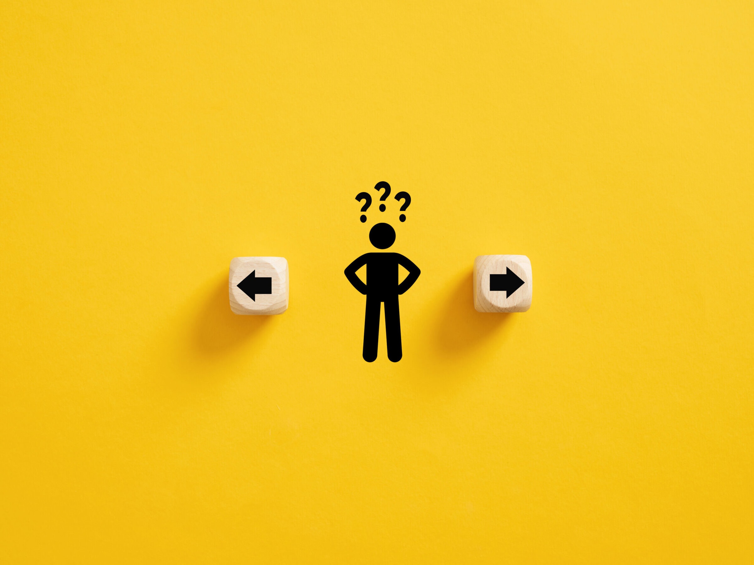 Decision making and choosing the right path. Confusion about deciding which direction to go. Stickman with question marks standing in between the wooden cubes with arrow symbols.
