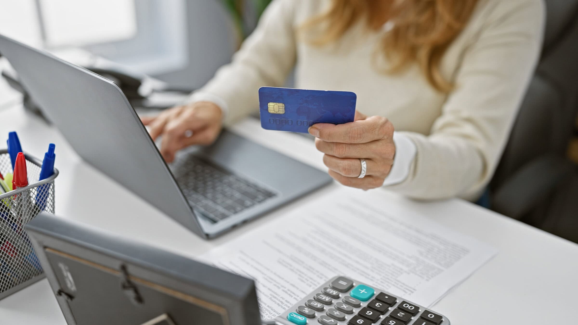Hispanic woman holding credit card and using laptop for online shopping in office