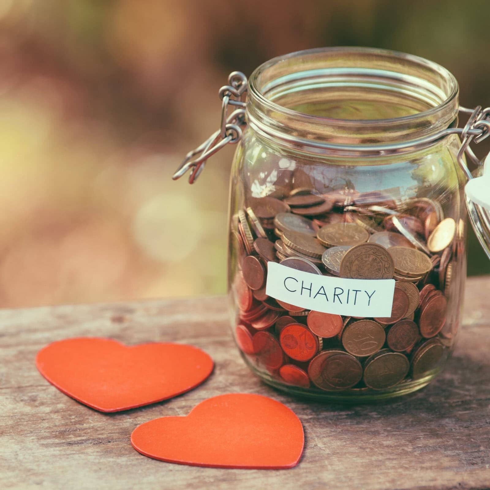 Money jar full of coins for charity and a couple of heart shapes