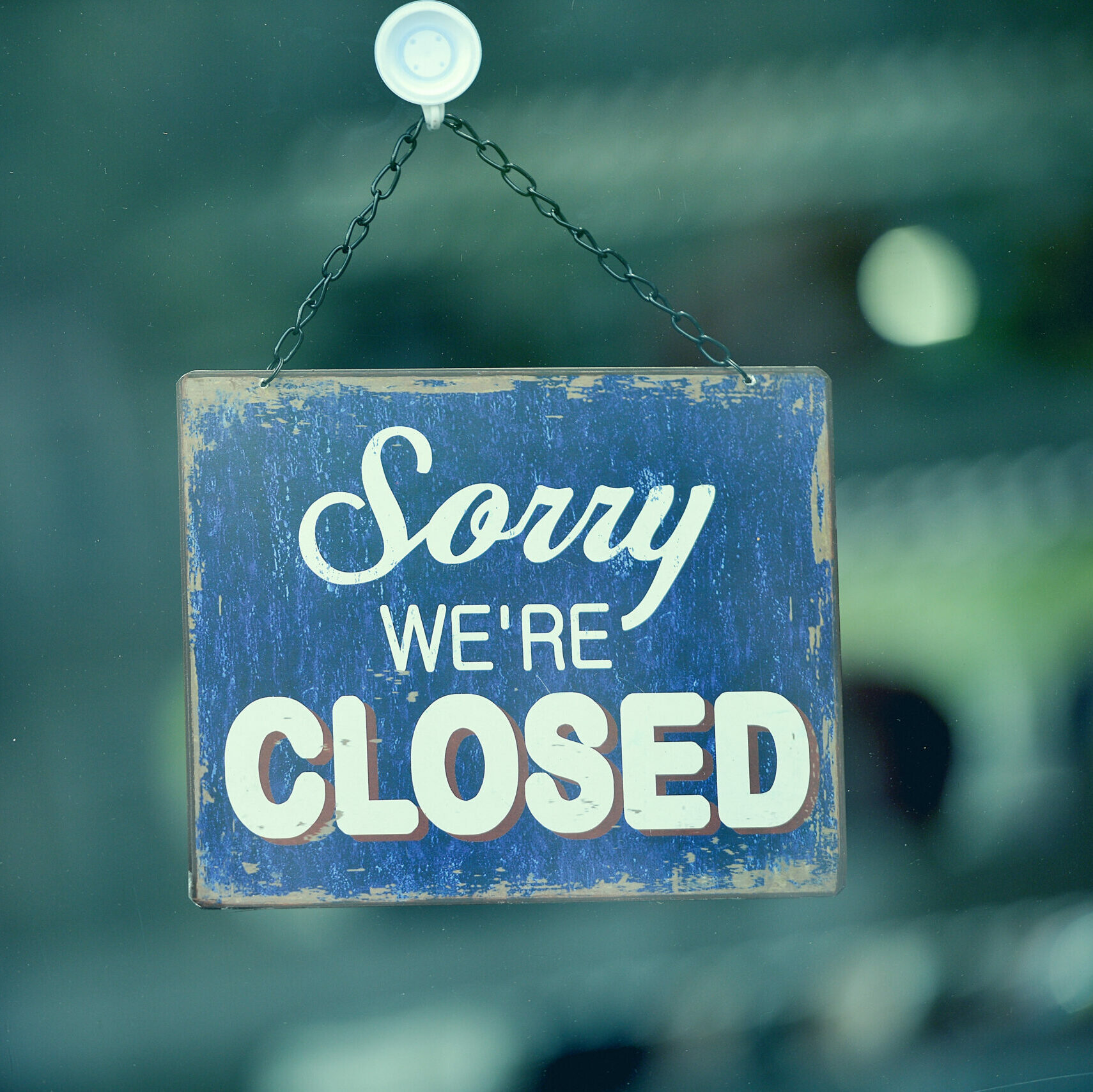 Close-up on a blue closed sign in the window of a shop displaying the message "Sorry we are closed"