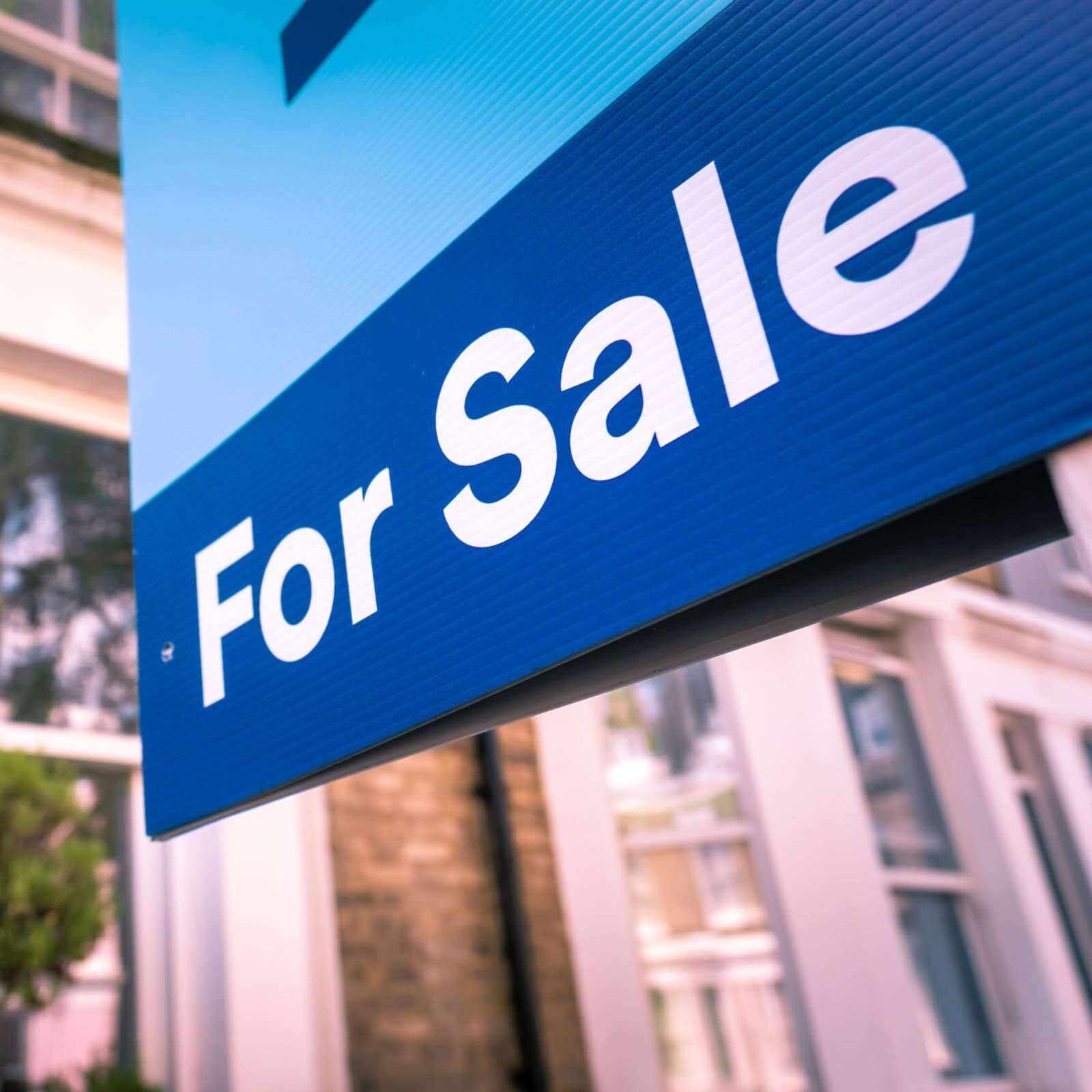 Estate agent 'For Sale' sign on street of houses