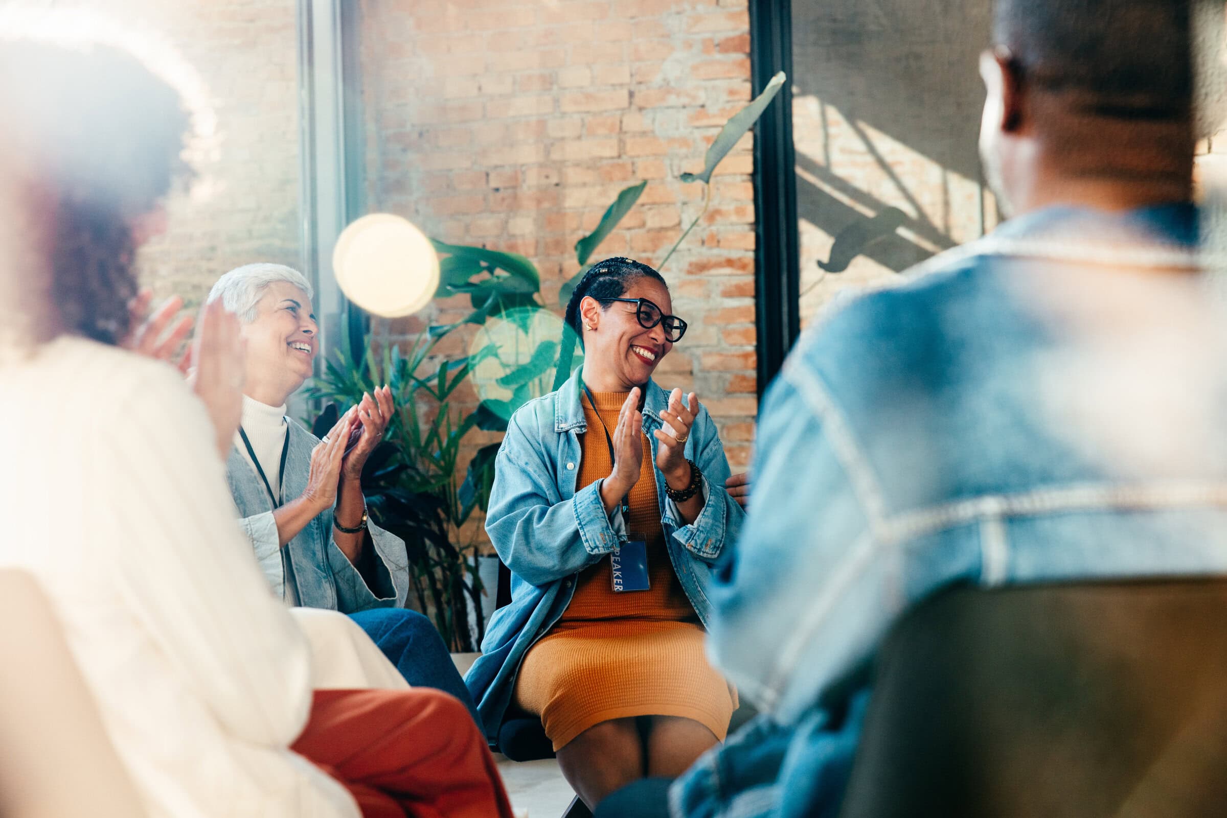 A group of happy people clapping, showing support and encouragement in a workshop environment with a positive atmosphere.
