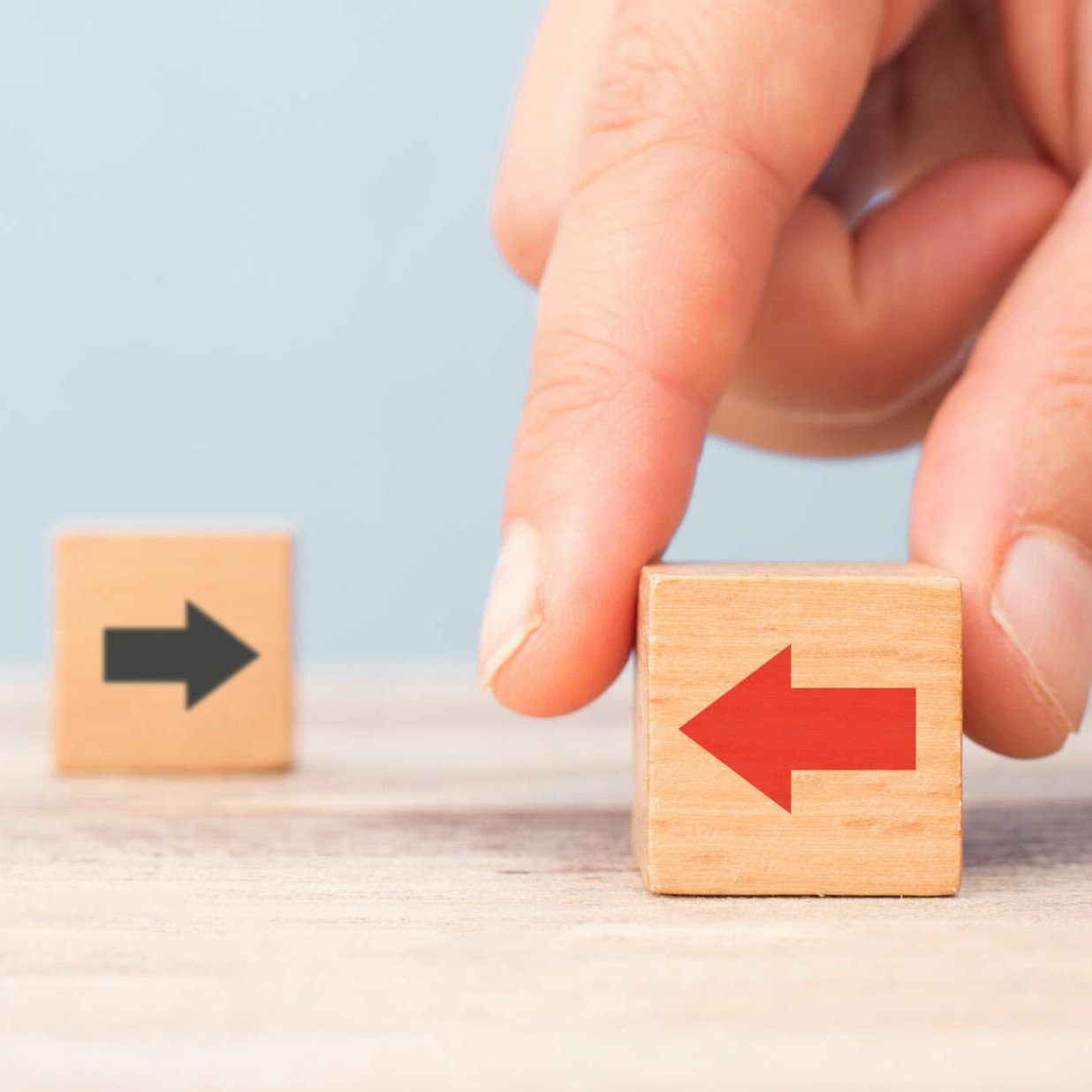 different thinking concept. Hand chooses red arrow facing opposite direction with black arrow