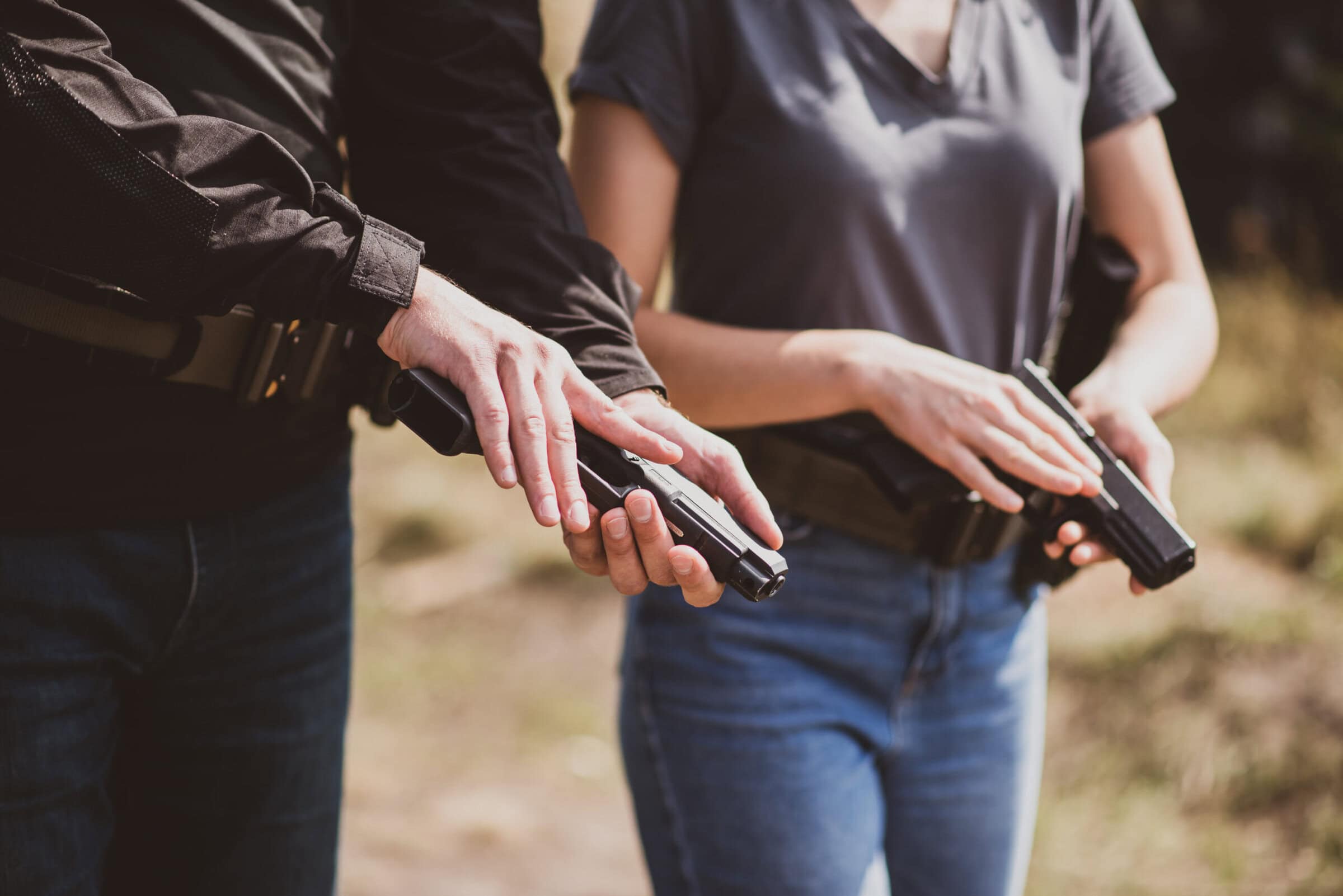 Shooting instructor teaching a woman how to properly handle a weapon at the shooting range