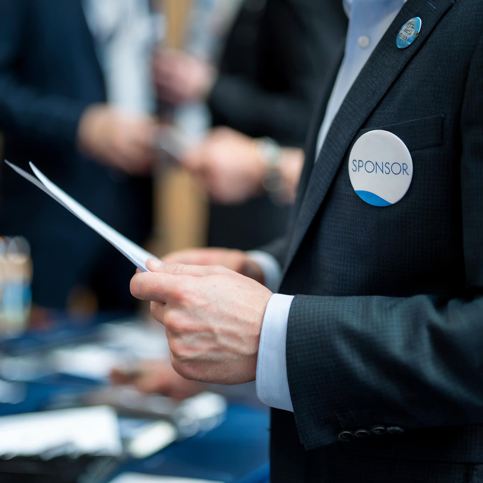 "SPONSOR" badge worn by a businessperson at a networking event.