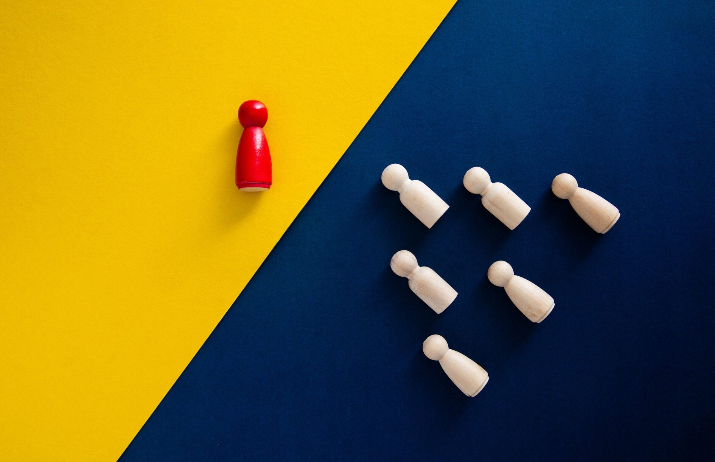 Red pawn standing out from the group of white pawns, representing leadership, different approach, and unique business strategy