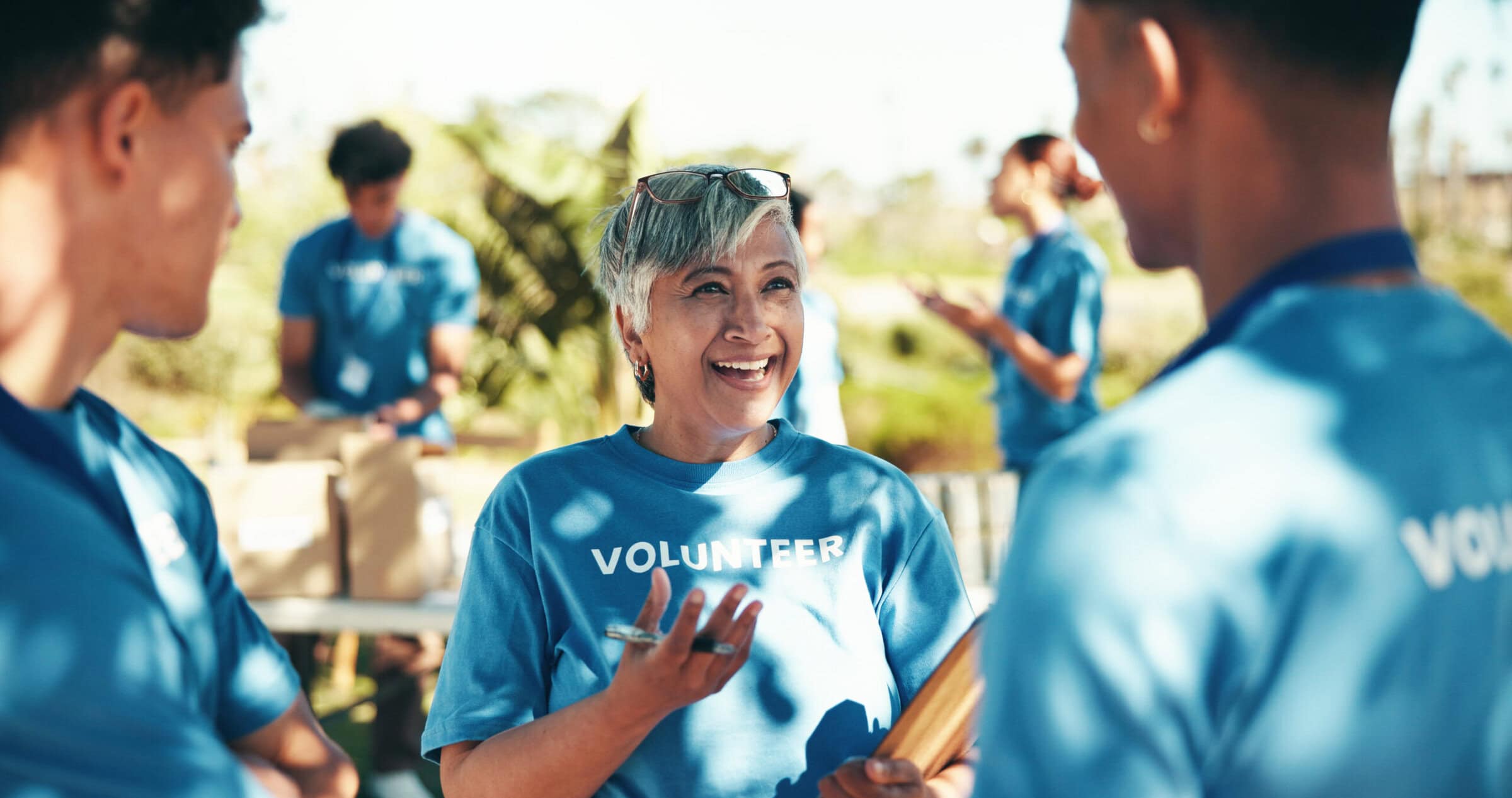 Teamwork, volunteers and happy for charity, group and success of fundraiser, discussion and mature woman. Outdoor, talking and coordinator with good news for people, community service and nonprofit.