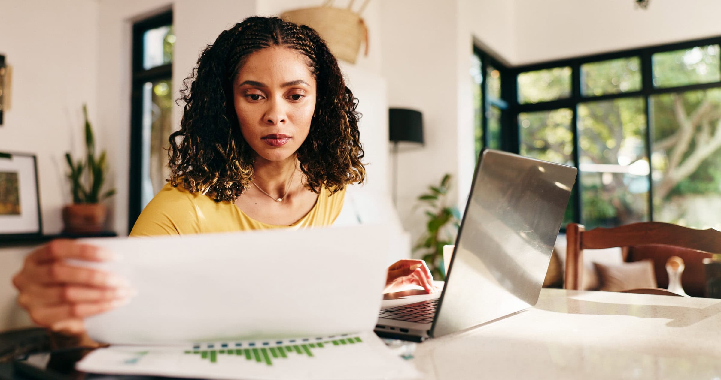 Woman, finance and paperwork with laptop for budget planning, review or analysis at home. Female person, freelancer or remote worker with documents, computer or financial report for expenses or bills.