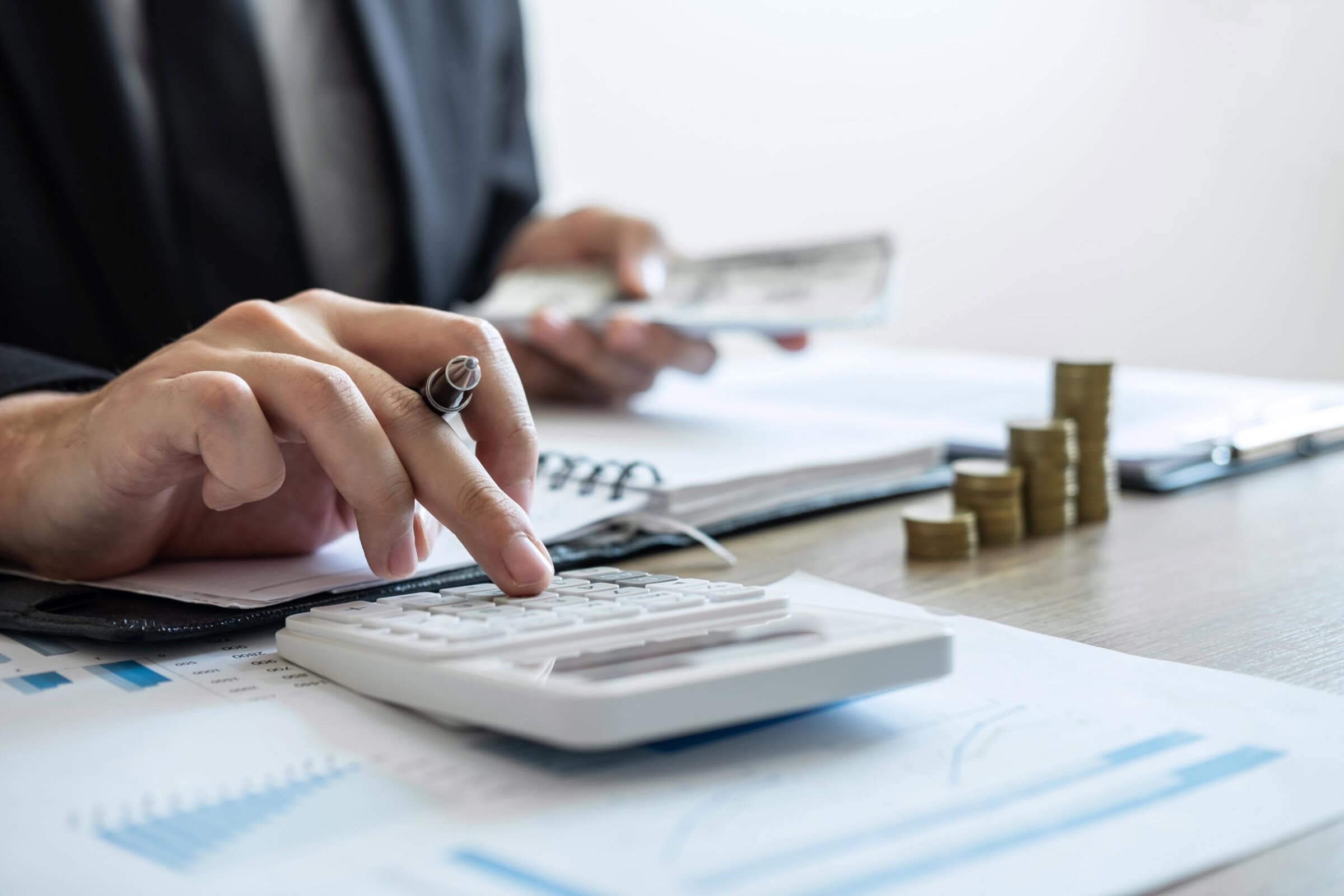 Businessman accountant counting money and making notes at report doing finances and calculate about cost of investment and analyzing financial data, Financing Accounting Banking Concept.