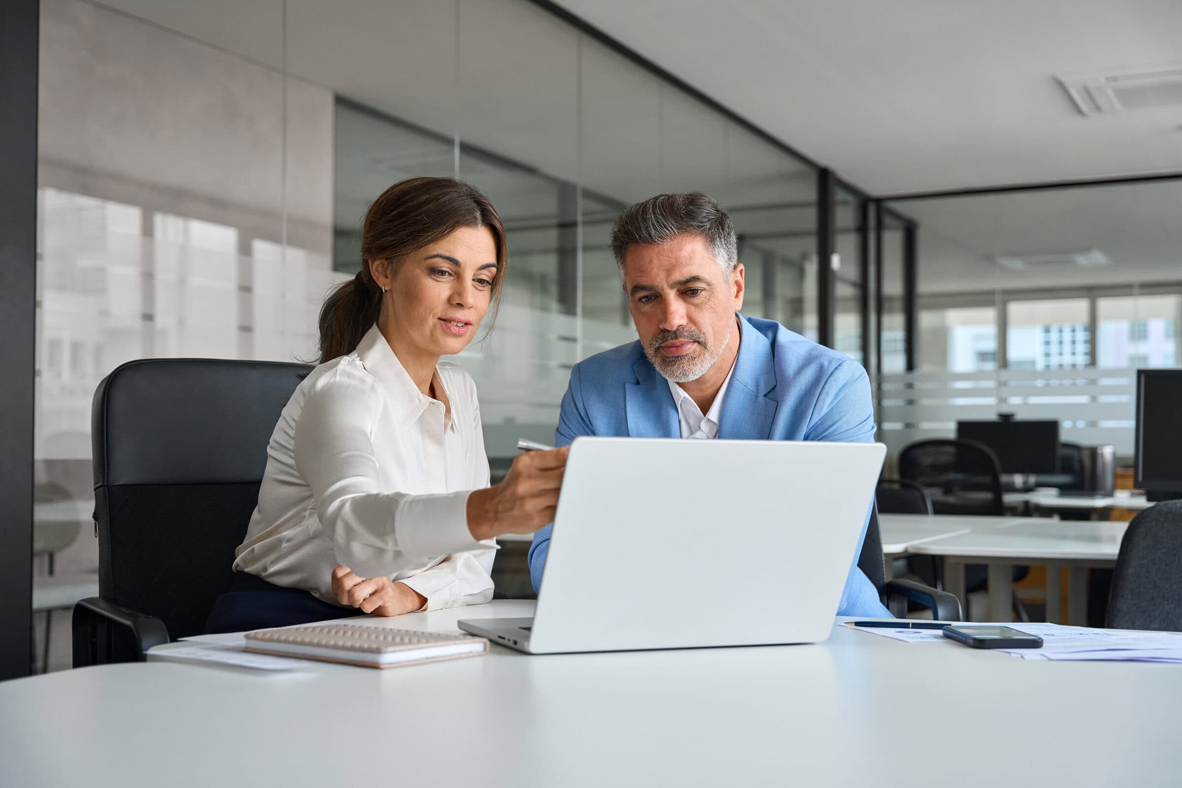 Professional bank manager consulting financial corporate client using laptop. Two busy professional executives team business people of middle age working together on computer at office meeting.